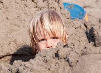 Parents bury 2-year-old child in the sand up to her neck under hot sun, while they fool around in the water