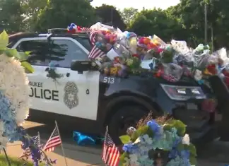 Car of fallen officer covered in flowers but a single note on plain white paper leaves it’s mark