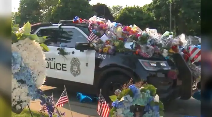 Car of fallen officer covered in flowers but a single note on plain white paper leaves it’s mark