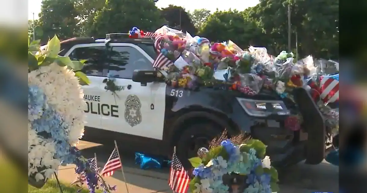 Car of fallen officer covered in flowers but a single note on plain ...