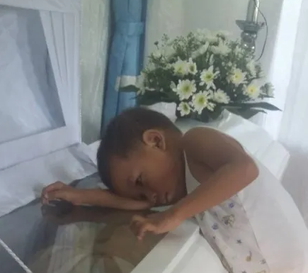 Child silently approaches mother’s coffin, presses head against it during service